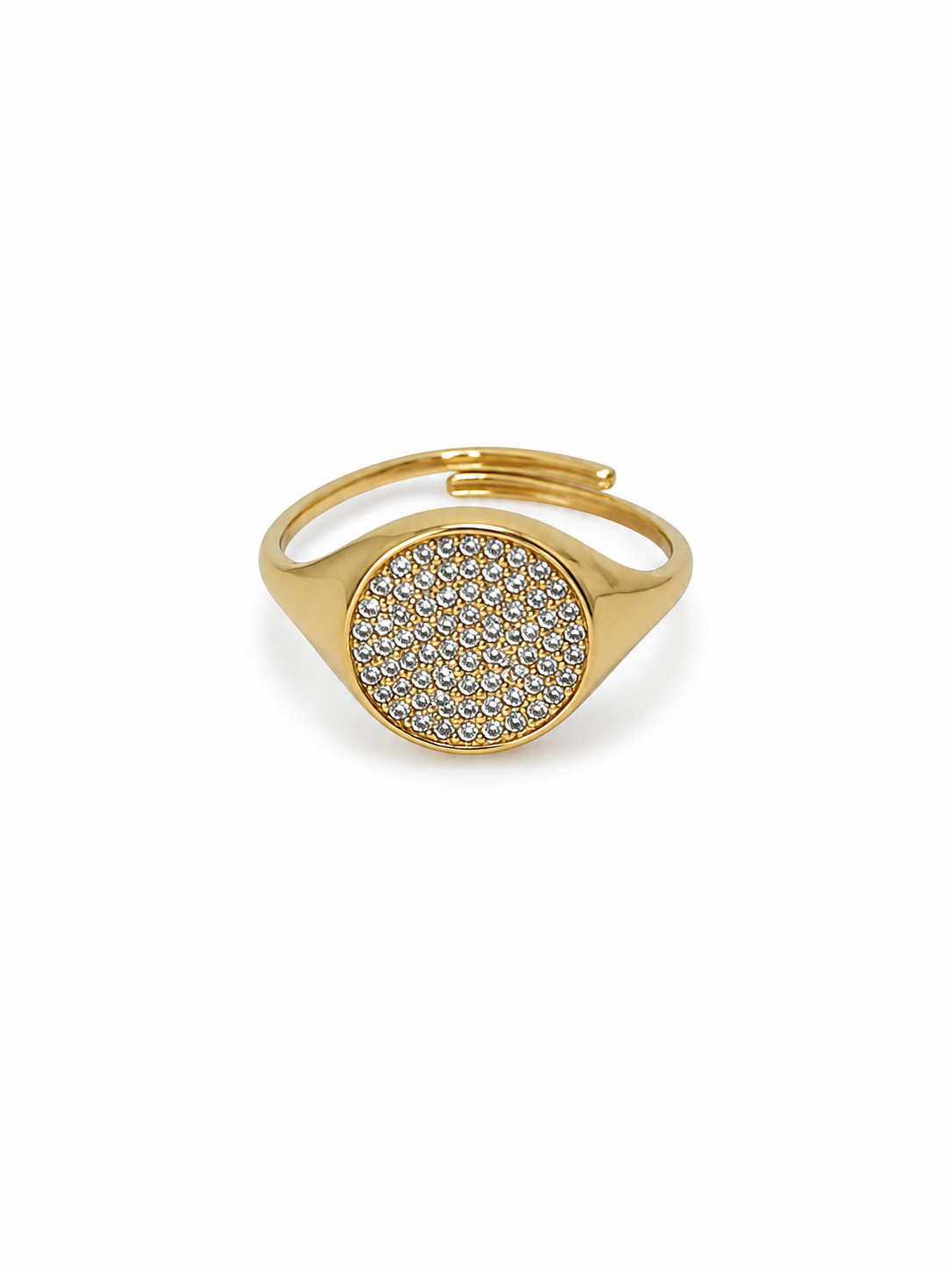 A gold signet-style ring with a round face paved with small clear stones, shown on a plain white background.