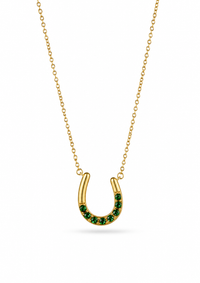 A gold horseshoe pendant necklace with a row of small green stones along the lower curve, displayed on a clean white background.